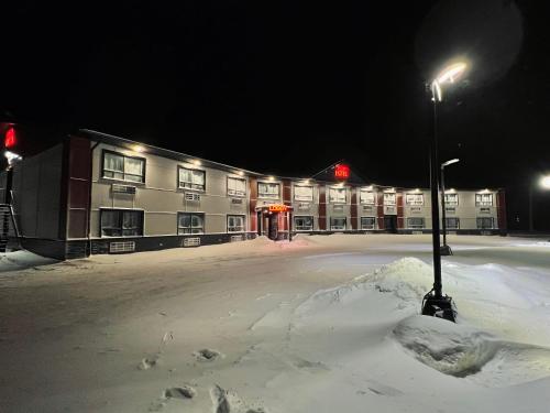 HWY 17 Hotel في واوا: موقف سيارات مغطى بالثلج أمام الفندق