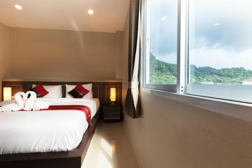 ein Schlafzimmer mit einem Bett und einem großen Fenster in der Unterkunft Pranee Home Phang-nga in Ban Khaek