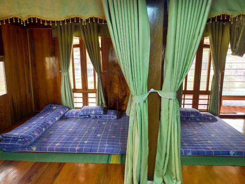 two beds in a room with green curtains at Homestay duy mạnh gần suối nước khoáng nóng trạm tấu in Cham Ta Lao