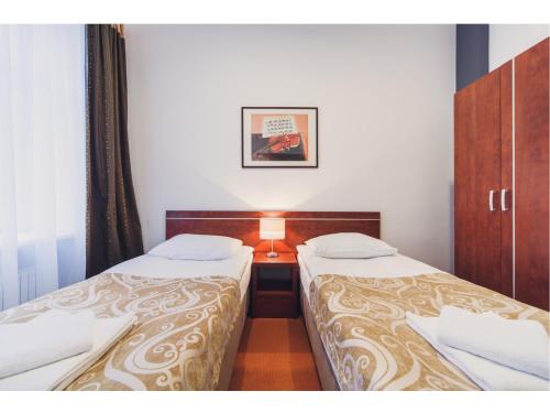 a room with two beds and a table with a lamp at Hotel Chmielna Warsaw in Warsaw