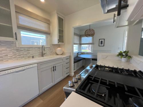 a kitchen with white cabinets and a stove top oven at El Nido Beachlife Cottage in South Bay Los Angeles in Redondo Beach