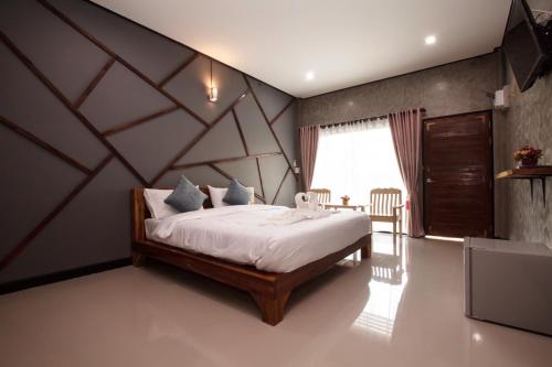 a bedroom with a large bed with a wooden headboard at โรงแรมบ้านมะกรูด Baan Ma Grood Hotel in Phayao