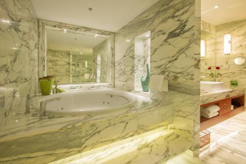 a bathroom with a tub and a large mirror at Avic Hotel Beijing in Beijing