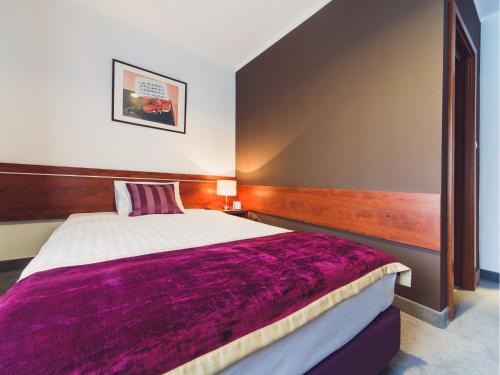 a bedroom with a large bed with a purple blanket at Hotel Chmielna Warsaw in Warsaw