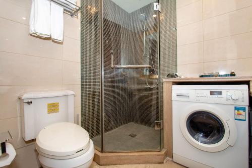 a bathroom with a shower and a washing machine at The Palace Service Apartment Beijing in Beijing