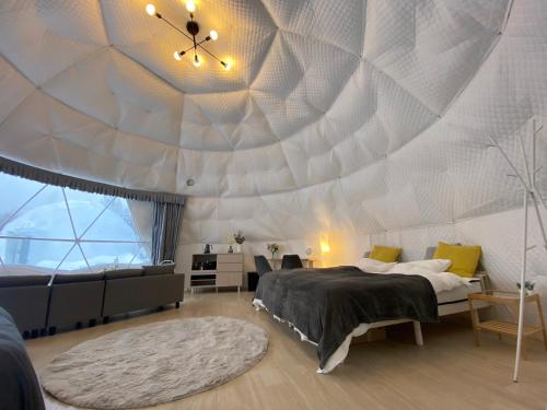 una camera da letto con soffitto a cupola, letto e divano di GRAMPING STAY TOMAMU a Tomamu