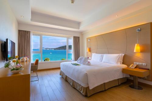 a hotel room with a large bed and a large window at Ocean View Resort Yalong Bay in Sanya