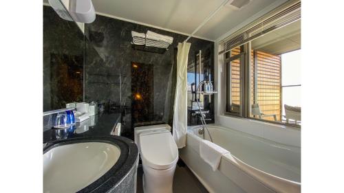 a bathroom with a tub and a toilet and a sink at Hotel Noborisaka in Fujikawaguchiko