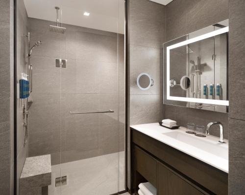 a bathroom with a shower and a sink and a mirror at Four Points by Sheraton Suwon in Suwon