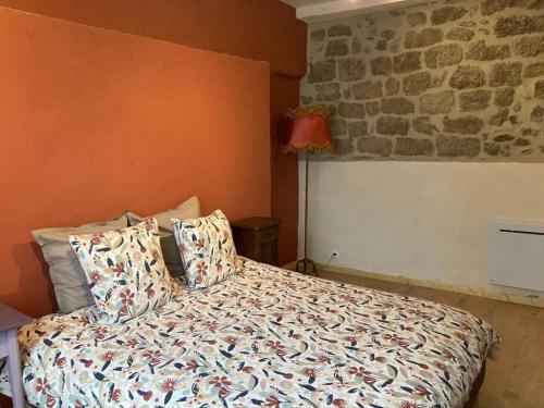 - une chambre dotée d'un lit avec des oreillers et d'un mur en pierre dans l'établissement Appartement Rez-de-chaussée, à Largentière