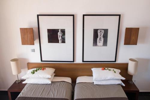 two beds in a room with two pictures on the wall at Hotel Esplanada in Dili