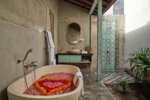 a bathroom with a bath tub filled with flowers at Casa Batu Belig in Seminyak