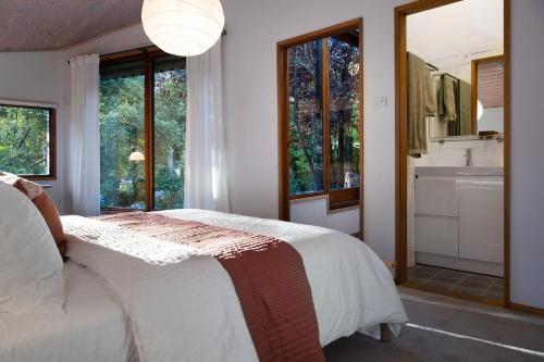 a bedroom with a large bed and a bathroom at Woodland Cottage in Daylesford