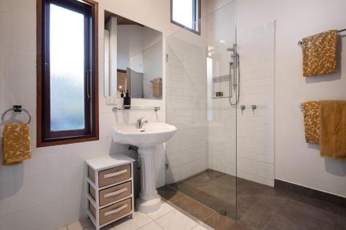 a white bathroom with a sink and a shower at Woodland Cottage in Daylesford