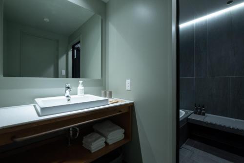 a bathroom with a sink and a mirror and a tub at KAIKA Tokyo by THE SHARE HOTELS in Tokyo