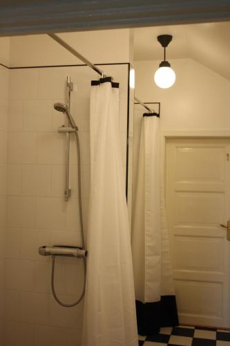 a shower with a white shower curtain in a bathroom at Borregården Bed & Breakfast in Borrby