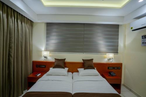 two beds in a room with two lamps and curtains at AS Inn in Ernakulam