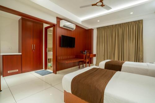a hotel room with two beds and a desk at AS Inn in Cochin
