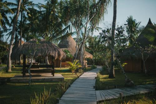 um caminho de madeira através de um resort com palmeiras em Le Nusa Beach Club em Nusa Lembongan