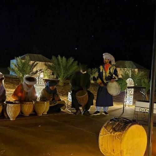 a group of people playing drums on a stage at Riad Hassi Labied Merzouga in Merzouga
