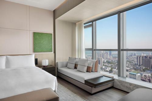 ein Schlafzimmer mit einem Bett und einem Sofa und einem großen Fenster in der Unterkunft JW Marriott Hotel Changsha in Changsha