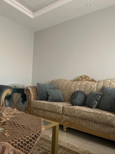 a living room with a brown couch with blue pillows at AlReem Apartment in Al Madinah