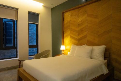 um quarto com uma cama branca e uma cabeceira em madeira em Khách sạn gần biển Karina Phú Yên em Liên Trì (4)