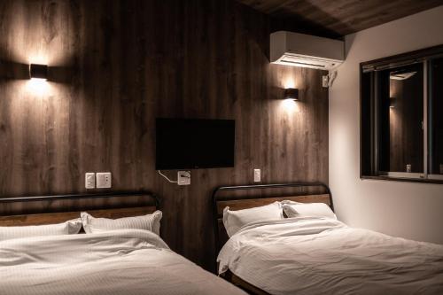 a bedroom with two beds and a tv on the wall at リゾートイン西表島 in Iriomote