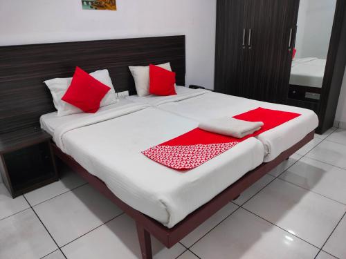 a large bed with red and white pillows on it at Kings Fort Rooms Thrippunithura in Ernakulam