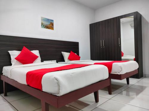 a bedroom with two beds with red and white pillows at Kings Fort Rooms Thrippunithura in Ernakulam