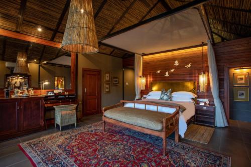 a bedroom with a bed and a desk in a room at Mukwa River Lodge in Livingstone