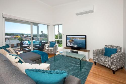 a living room with a couch and chairs and a television at Minnamurra Beach Bliss Minnamurra in Minnamurra