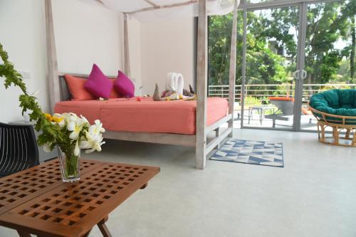 Eldezo Relax Paradise (Pvt) Ltd في بينتوتا: غرفة نوم بسرير وطاولة مع إناء من الزهور