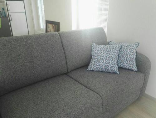 a gray couch with two pillows on it in a room at Moderni avara yksiö Jyväskylän ydinkeskustassa in Jyväskylä