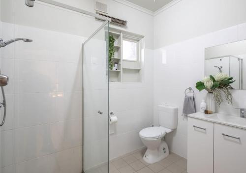 a white bathroom with a toilet and a shower at Glenelg Beach House With Private Beachfront Pool in Glenelg