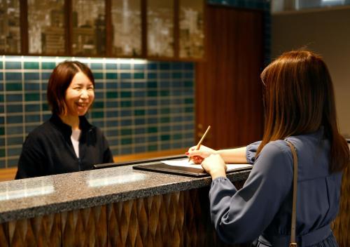 a woman sitting at a counter talking to another woman at Travelodge Sapporo Susukino in Sapporo