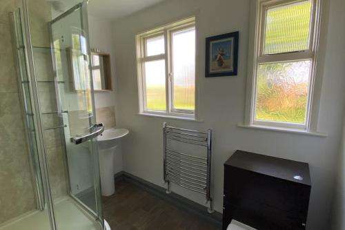 a bathroom with a glass shower and a sink at Cheerful 3 bedroom bungalow with indoor fire place in Gloucester