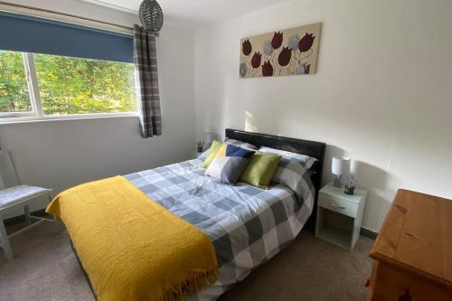 a bedroom with a bed with a yellow and blue blanket at Cheerful 3 bedroom bungalow with indoor fire place in Gloucester