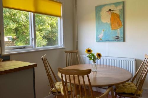 a dining room table with a vase of flowers on it at Cheerful 3 bedroom bungalow with indoor fire place in Gloucester