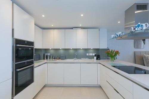 a white kitchen with white cabinets and a sink at Monowai Heights in St Ives