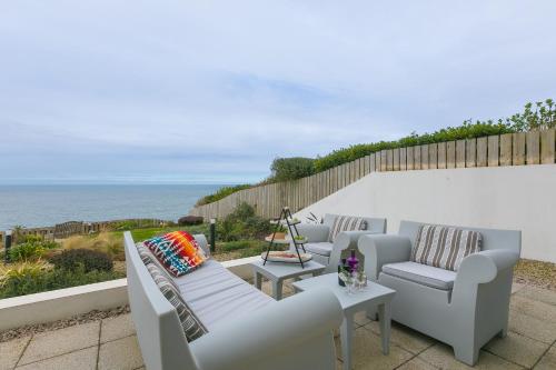 a group of chairs and tables on a patio with the ocean at Monowai Heights in St Ives