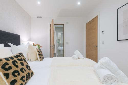 a white bedroom with a large white bed with pillows at Monowai Heights in St Ives