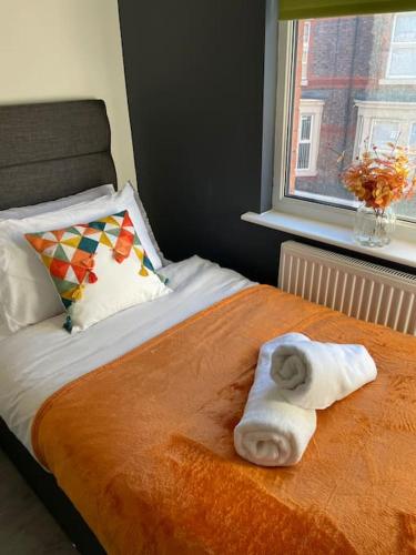ein Bett mit einem Handtuch darauf mit einem Fenster in der Unterkunft Luxury home in Anfield in Liverpool