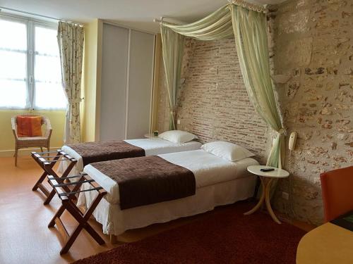sypialnia z 2 łóżkami i ceglaną ścianą w obiekcie Le Grand Monarque Donzy w mieście Donzy