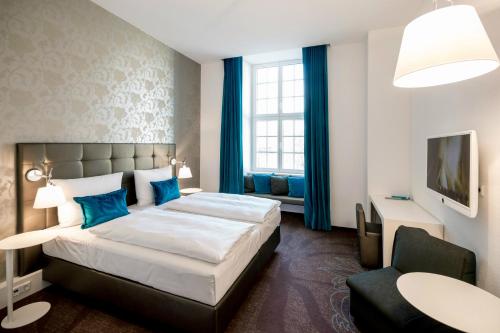 Habitación de hotel con cama y silla en Motel One Magdeburg en Magdeburgo