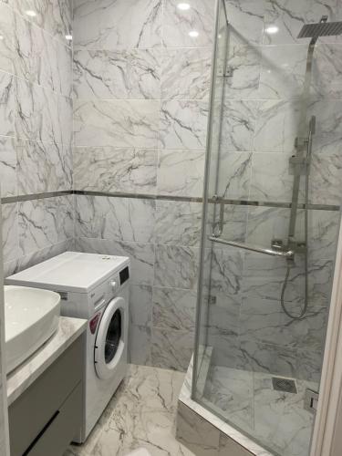 a bathroom with a shower and a washing machine at 1 комн квартира in Oral