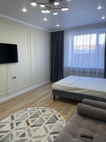 a bedroom with a bed and a flat screen tv at 1 комн квартира in Oral