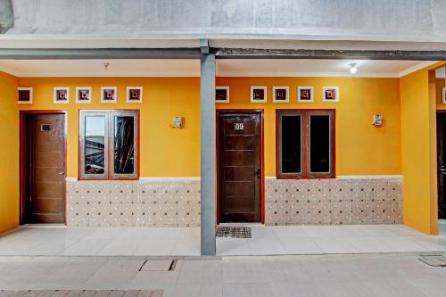 a row of doors on a building with yellow walls at Hotel O Amole Paviliun Syariah in Cilacap