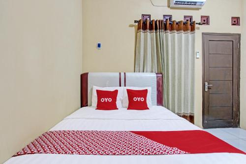 a bedroom with a bed with two red pillows at Hotel O Amole Paviliun Syariah in Cilacap