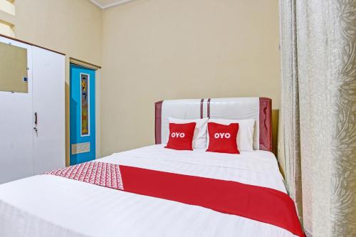 a bedroom with a bed with two red pillows at Hotel O Amole Paviliun Syariah in Cilacap